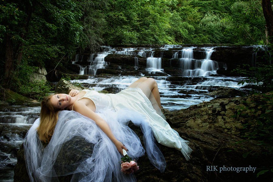 bride lying on a rock by a waterfall